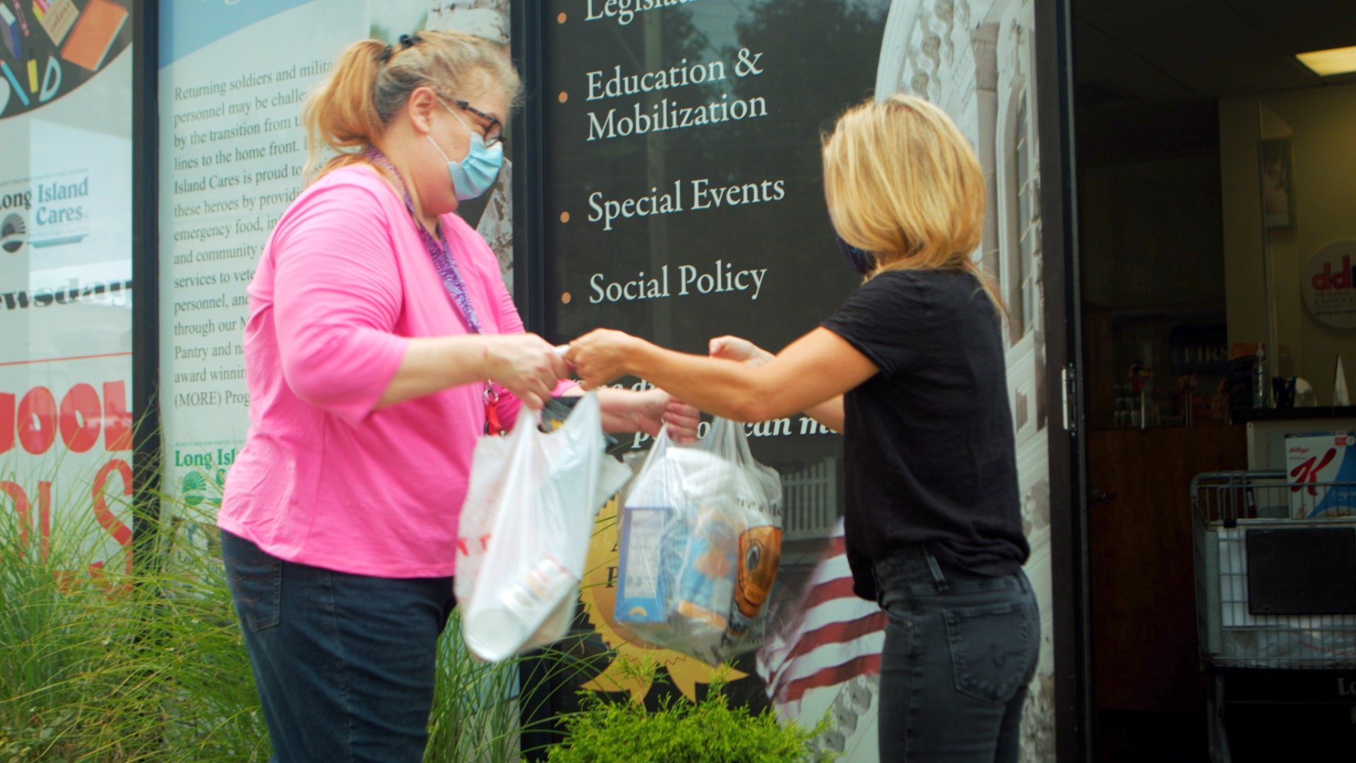 Middle age woman accepting a food donation from Long Island Cares volunteer